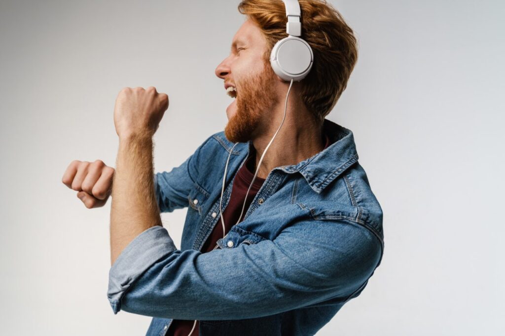 happy handsome redhead guy in headphones singing and dancing